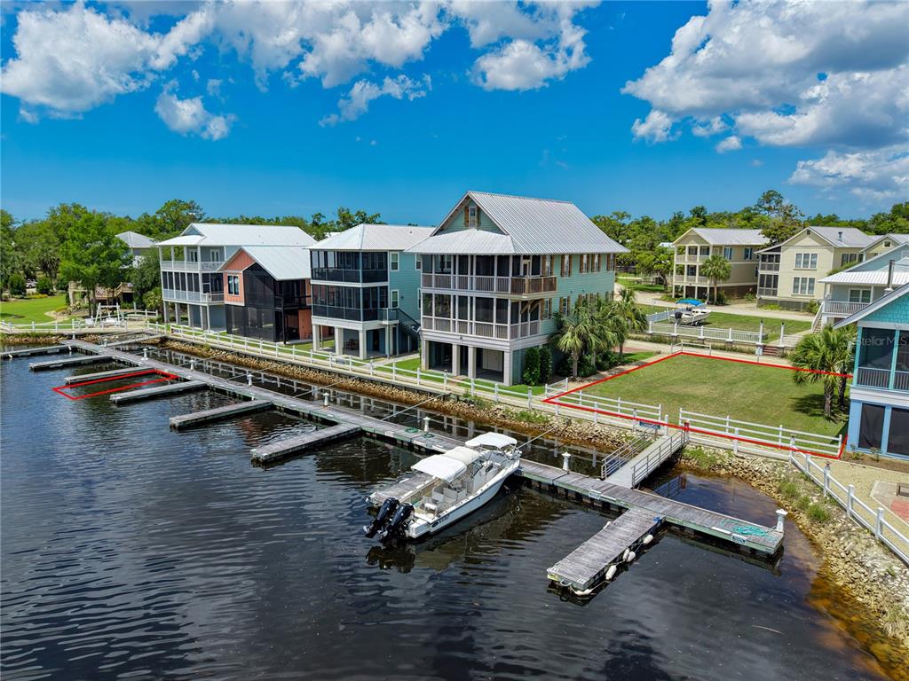 An aerial view shows waterfront houses with private boat docks and a vacant grassy lot — 140 RYLAND CIRCLE, STEINHATCHEE, FL