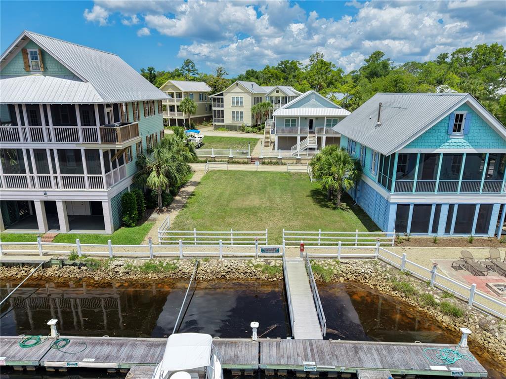 An aerial view shows a vacant grassy lot situated between two houses along a canal — 140 RYLAND CIRCLE, STEINHATCHEE, FL