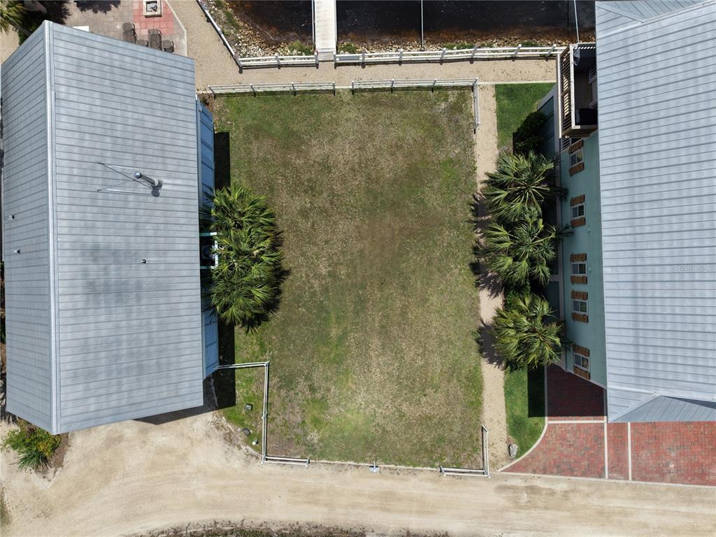 An aerial view shows a rectangular grassy lot situated between two buildings near a waterfront — 140 RYLAND CIRCLE, STEINHATCHEE, FL