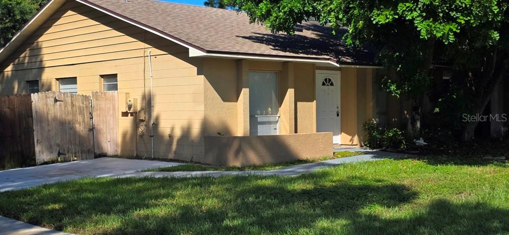 A tan, single-story house features a white front door, a wooden fence, and a lawn — 3302 ROYAL STREET, WINTER PARK, FL