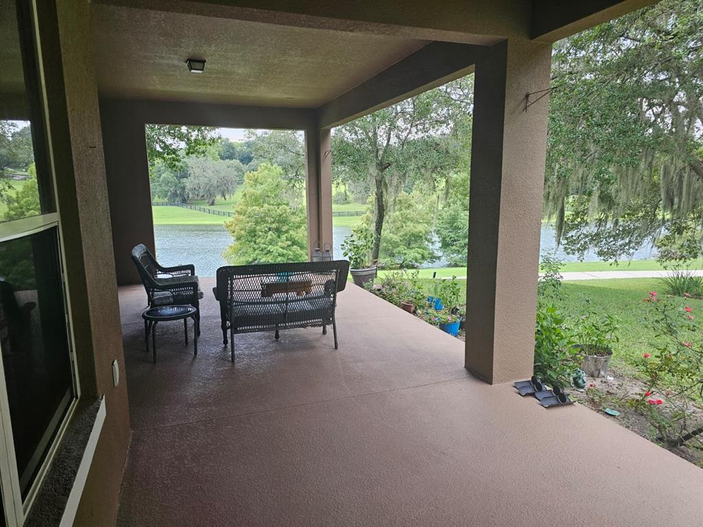 A living room with tile floors, a television, and a view of a lake outside — 21632 HIDDEN CREEK, MOUNT DORA, FL