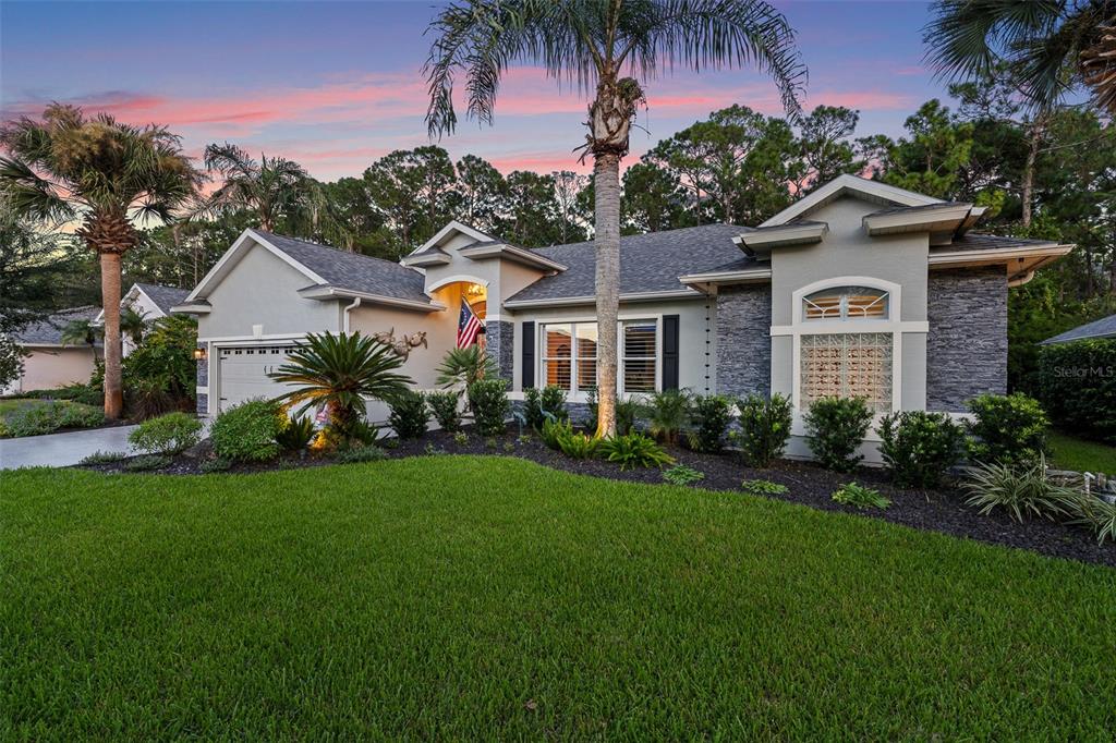 A single-story suburban house with a gray stone facade, a garage, and a palm tree — 109 BAY LAKE DRIVE, ORMOND BEACH, FL