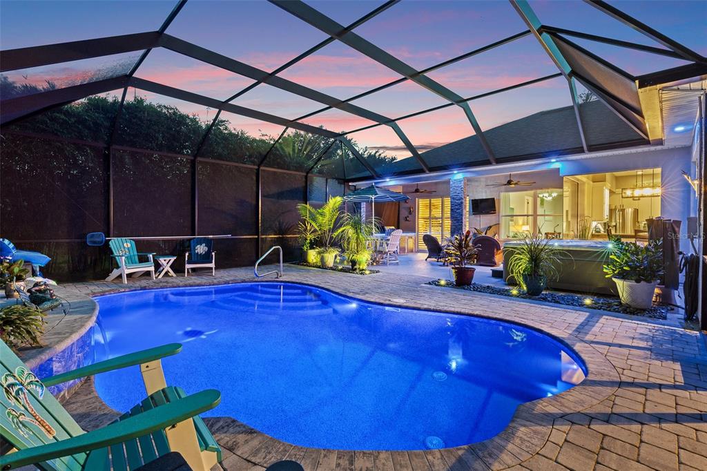 A screened-in patio features a swimming pool, a hot tub, and outdoor seating at sunset — 109 BAY LAKE DRIVE, ORMOND BEACH, FL