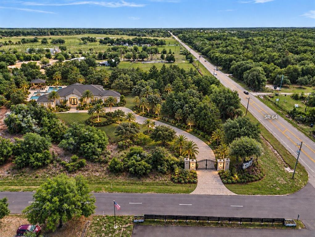 An aerial view shows a wooded lot situated between two paved roads — SR-64 E, MYAKKA CITY, FL