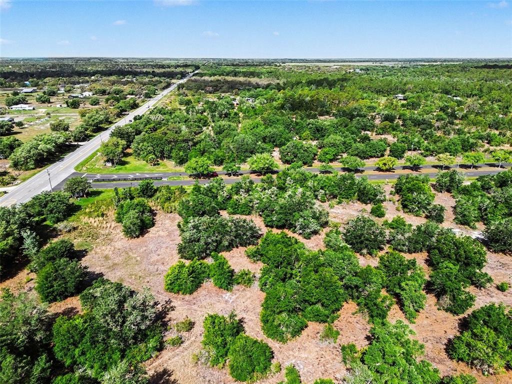 An aerial view shows a wooded, undeveloped lot adjacent to a paved road and highway — SR-64 E, MYAKKA CITY, FL