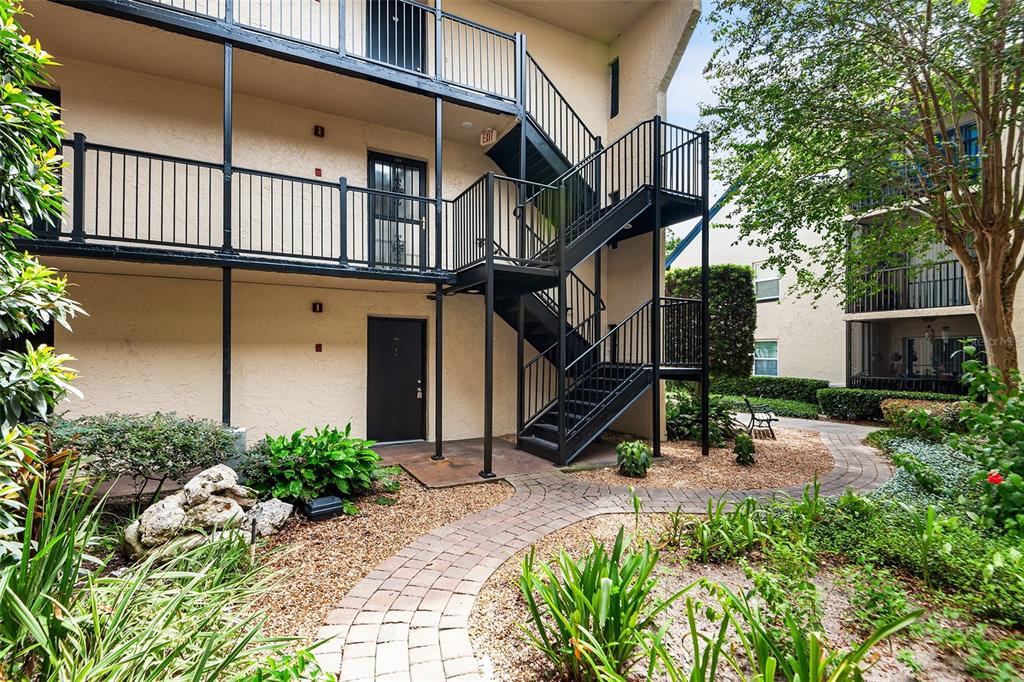 An exterior view of a multi-story apartment building featuring a black metal staircase and walkway — 2025 SYLVESTER ROAD UNIT N101, LAKELAND, FL