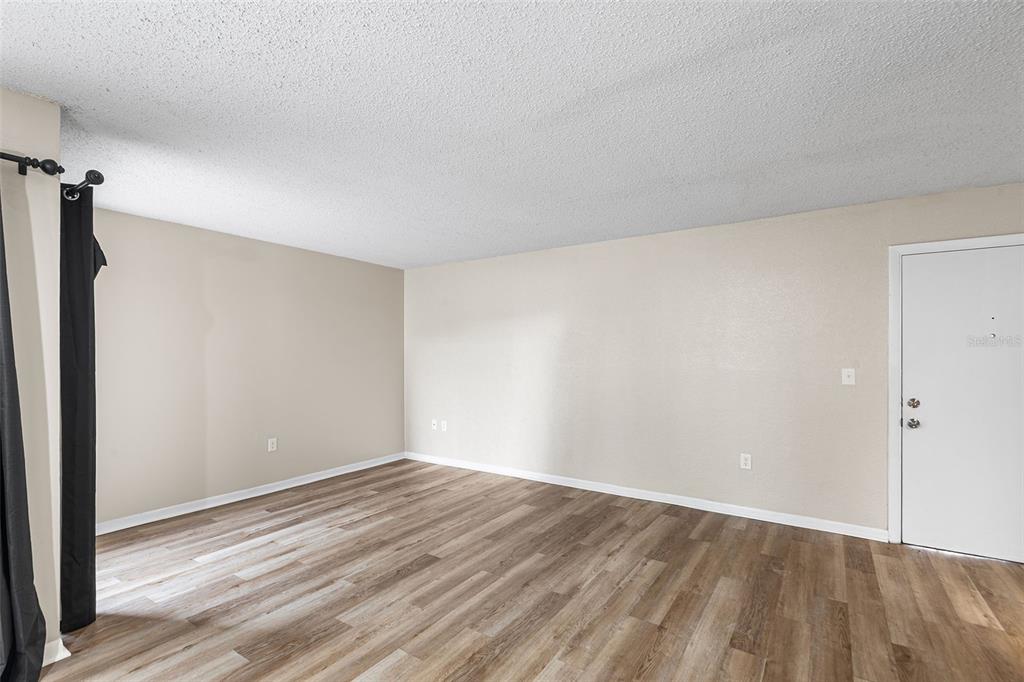 An empty room with light-colored walls, wood-look flooring, and a white entry door — 2025 SYLVESTER ROAD UNIT N101, LAKELAND, FL