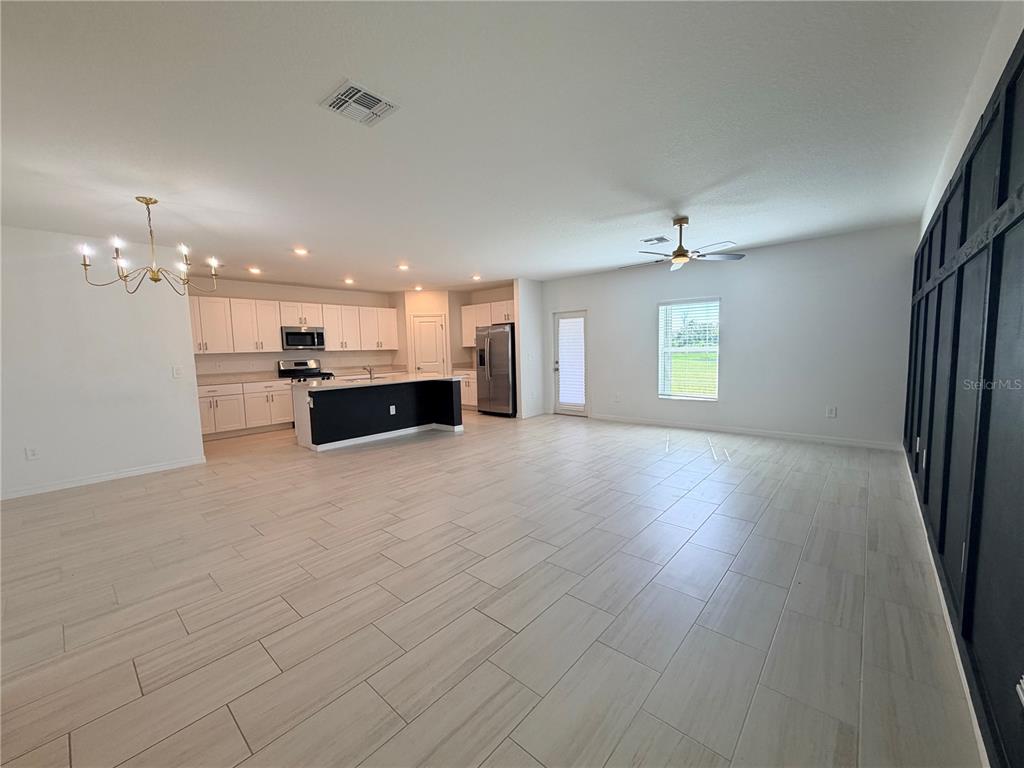 An open-concept kitchen and living area features white cabinetry, a black island, and tile flooring — 12490 SWEET ANGEL AURA WAY, PARRISH, FL
