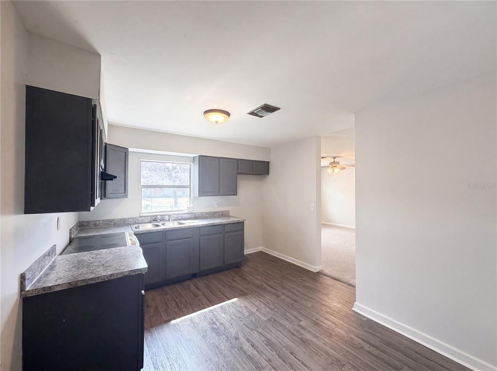 A kitchen features dark gray cabinets, laminate countertops, a white stove, and wood-look flooring — 1100 CAREFREE COVE DRIVE, WINTER HAVEN, FL