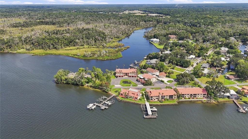 An aerial view shows waterfront apartment buildings with docks on a river near a forest — 352 NW 14TH PLACE UNIT 26, CRYSTAL RIVER, FL