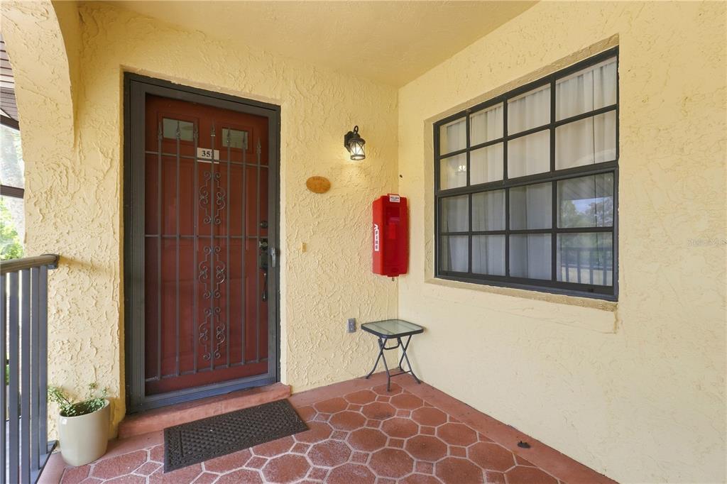 A covered entryway features a red door with a security gate and a fire extinguisher — 352 NW 14TH PLACE UNIT 26, CRYSTAL RIVER, FL