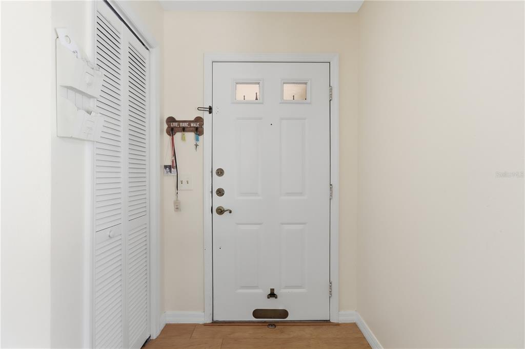 A white front door with two small windows is positioned next to a louvered closet door — 352 NW 14TH PLACE UNIT 26, CRYSTAL RIVER, FL
