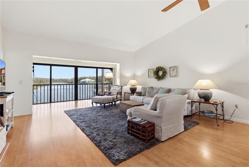 A living room with hardwood floors, a large area rug, and sliding doors overlooking water — 352 NW 14TH PLACE UNIT 26, CRYSTAL RIVER, FL