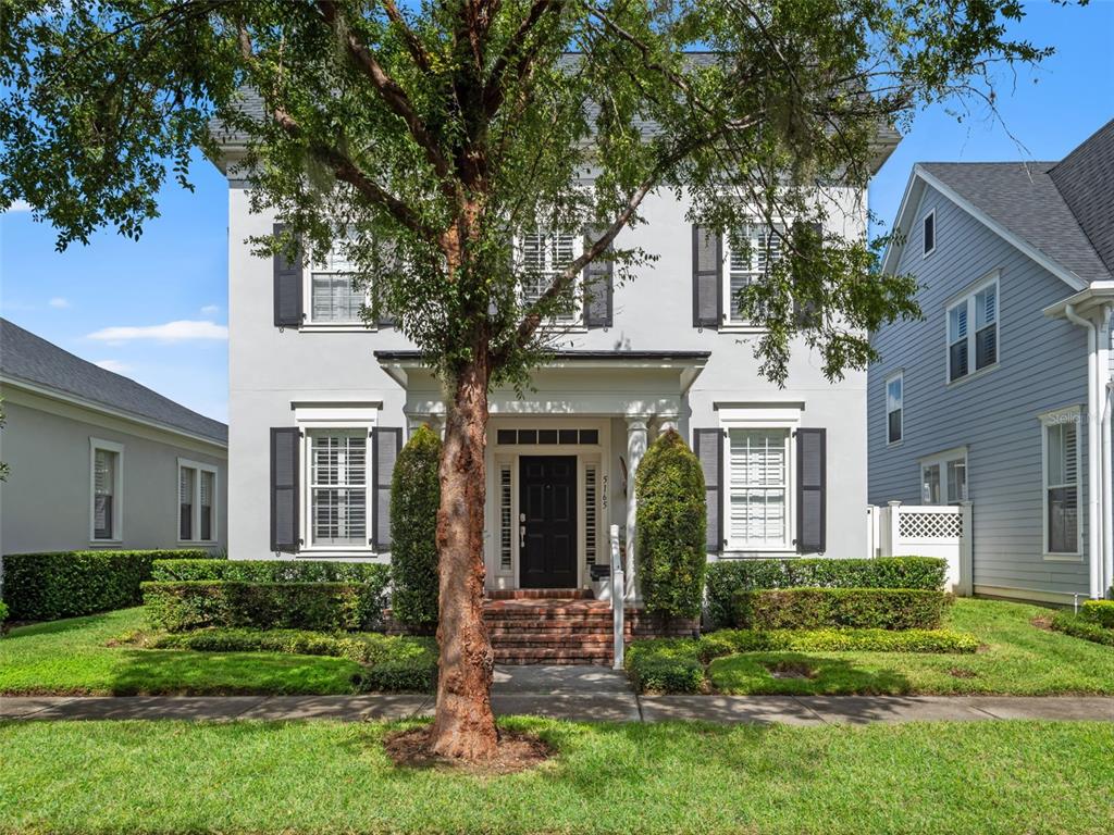 A two-story house with a white stucco facade, black shutters, and a front porch — 5165 FENWOOD LANE, ORLANDO, FL
