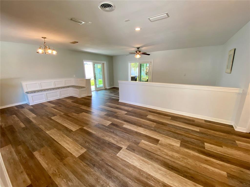 A spacious room features wood-look flooring, a built-in corner bench, and sliding glass doors — 809 JACARANDA DRIVE, LARGO, FL