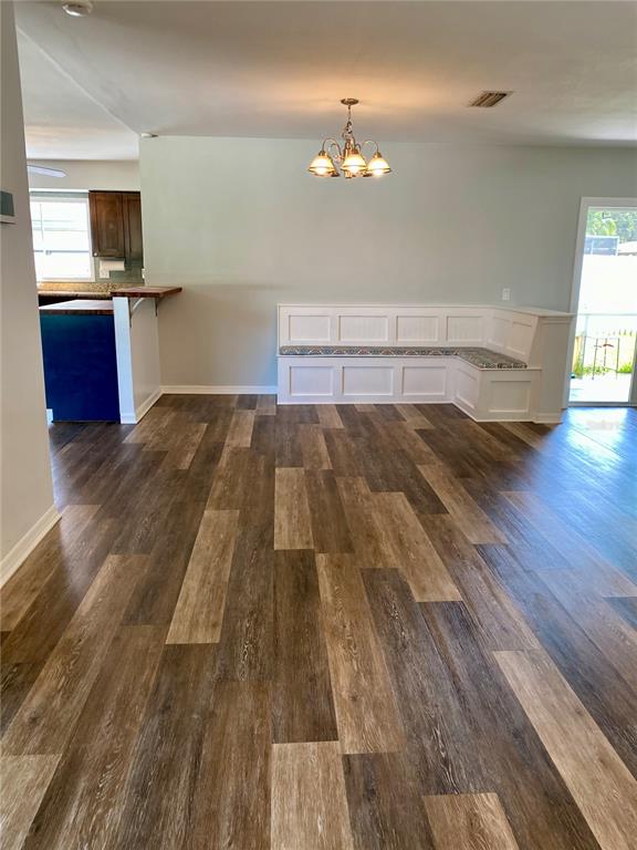 A dining area features wood-look flooring, a built-in corner bench, and a hanging light fixture — 809 JACARANDA DRIVE, LARGO, FL