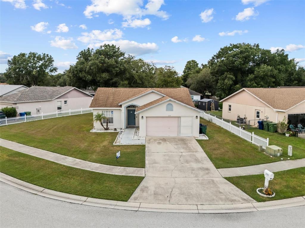 A single-story suburban house with a tan exterior, a two-car garage, and a white fence — 233 KINGS POND AVENUE, WINTER HAVEN, FL