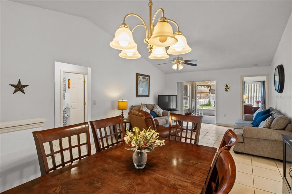 A dining area with a wooden table and chandelier opens into a living room — 233 KINGS POND AVENUE, WINTER HAVEN, FL