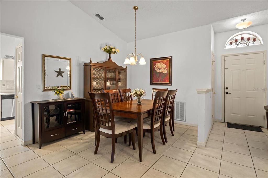 A dining room features a wooden table, chairs, a hutch, and tile flooring — 233 KINGS POND AVENUE, WINTER HAVEN, FL