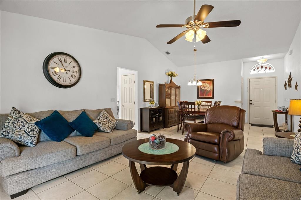 A living room with a gray sofa, brown leather recliner, round coffee table, and dining area — 233 KINGS POND AVENUE, WINTER HAVEN, FL