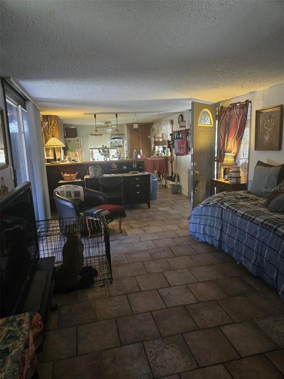 A living area with tile flooring, a bed, a desk, and a dog crate — 120 WEST LOOP, OAK HILL, FL