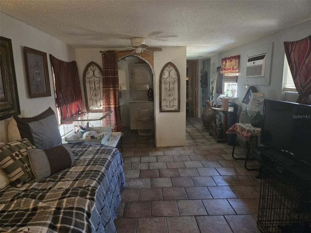 A room with tile flooring, a bed, a television, and an arched laundry area — 120 WEST LOOP, OAK HILL, FL