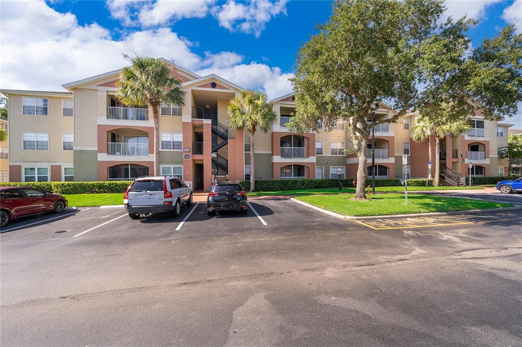 A multi-story apartment building with balconies and a parking lot in the foreground — 1939 SUMMER CLUB DRIVE UNIT 115, OVIEDO, FL