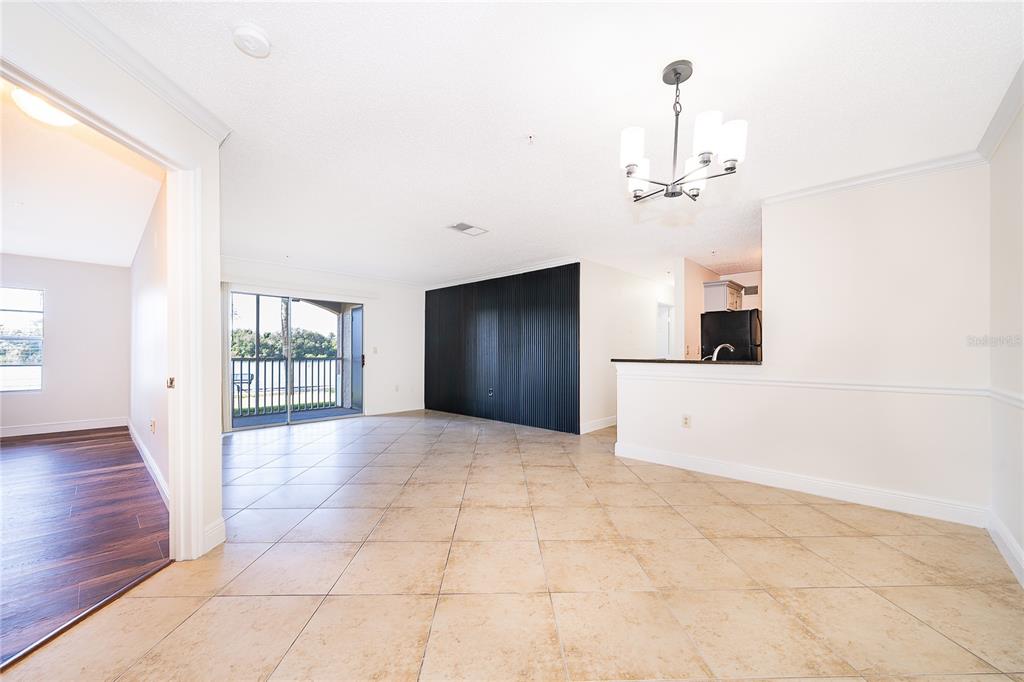An open-concept living area features beige tile flooring, a black accent wall, and a balcony — 1939 SUMMER CLUB DRIVE UNIT 115, OVIEDO, FL