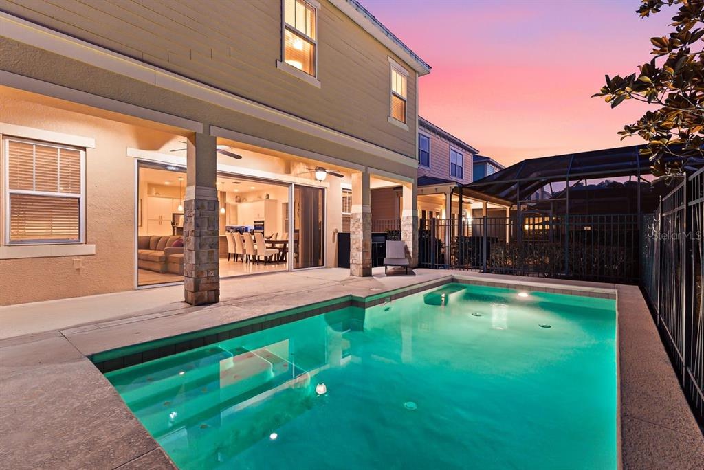 A backyard swimming pool sits in front of a two-story house with a covered patio — 1437 FAIRVIEW CIRCLE, REUNION, FL