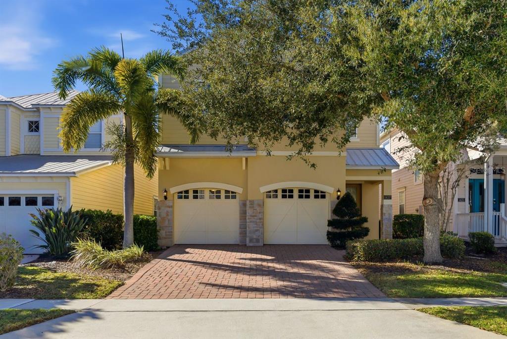 A two-story yellow house with a brick driveway and two garage doors — 1437 FAIRVIEW CIRCLE, REUNION, FL