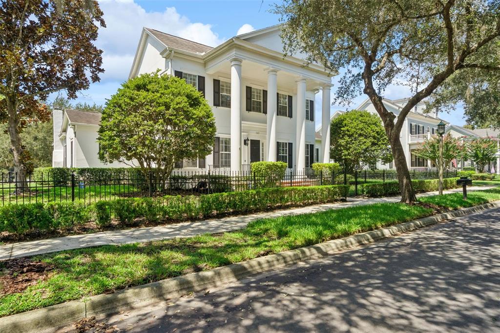 A two-story white colonial-style house features large columns, black shutters, and a front iron fence — 843 OAK SHADOWS ROAD, CELEBRATION, FL