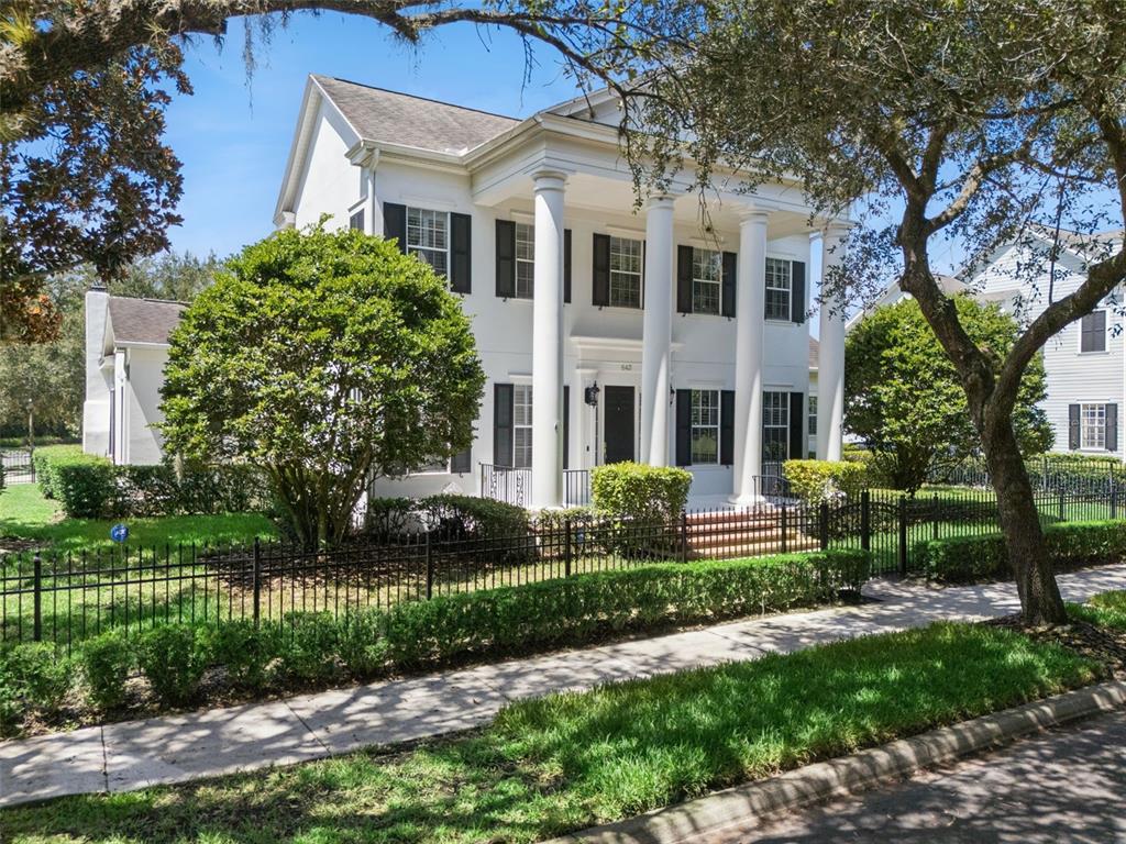 A white two-story house features a prominent front porch with tall columns and black shutters — 843 OAK SHADOWS ROAD, CELEBRATION, FL