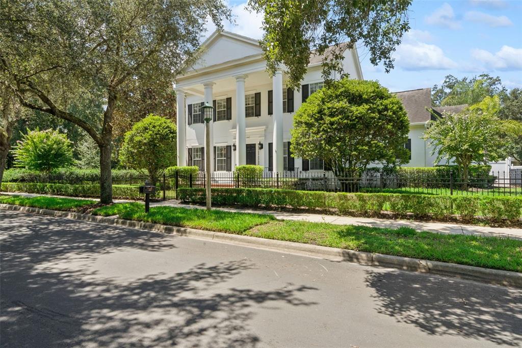A two-story white house with tall columns, black shutters, and a gated brick walkway — 843 OAK SHADOWS ROAD, CELEBRATION, FL
