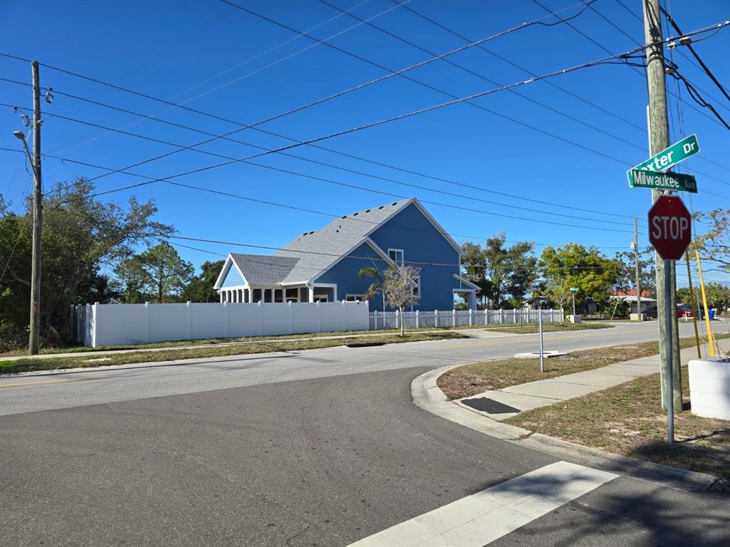 A blue two-story house with a white fence stands at the corner of a street — MILWAUKEE AVENUE, DUNEDIN, FL