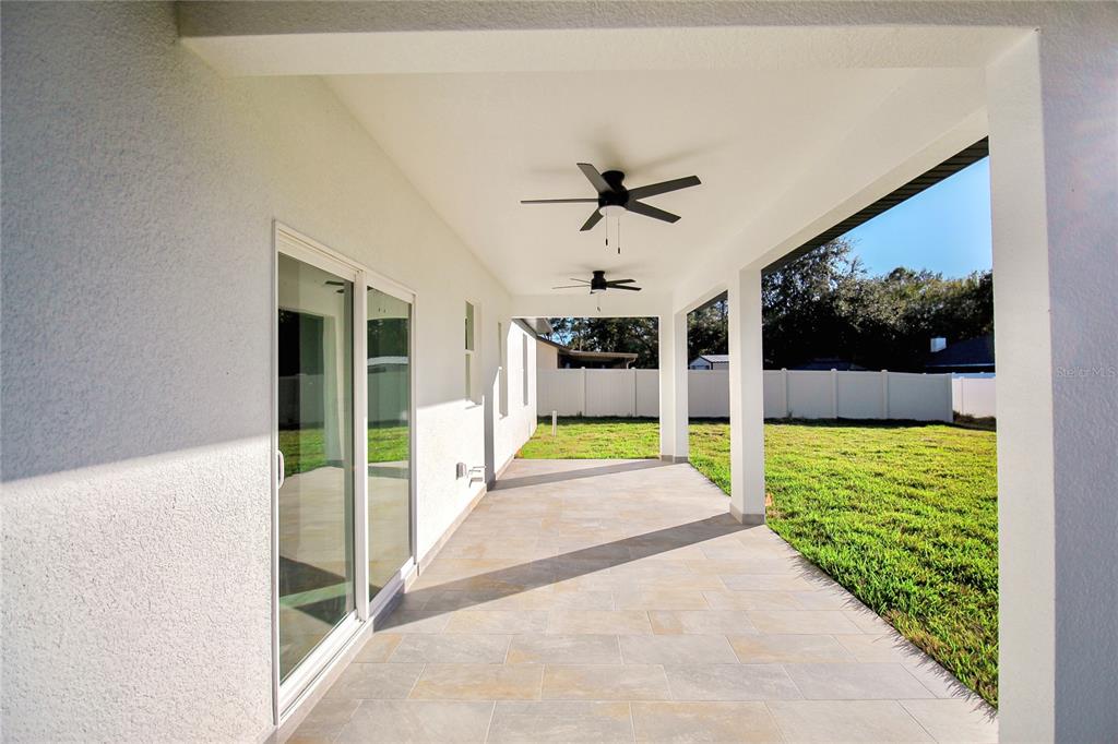 A covered patio with tiled flooring, two ceiling fans, and a view of the backyard — 3915 EL RADO AVENUE, SEBRING, FL