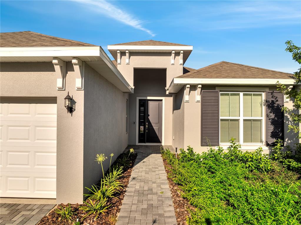 A single-story house exterior features a paved walkway leading to a dark front door — 2272 SIRENS LANE, MOUNT DORA, FL
