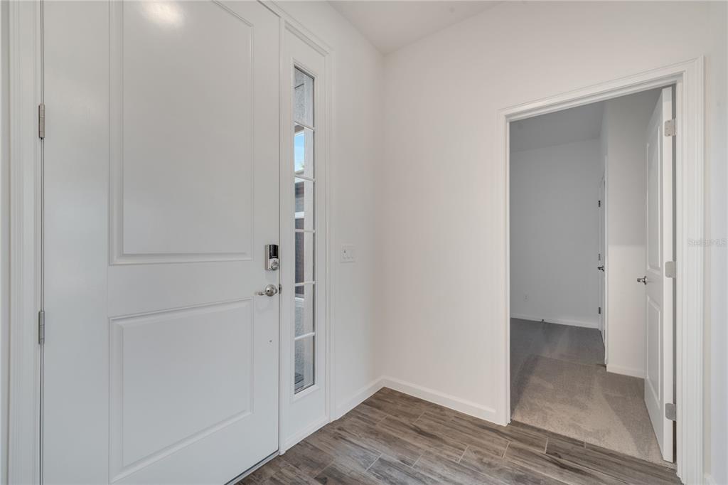 An entryway features a white front door with a sidelight, wood-look tile, and an open doorway — 2272 SIRENS LANE, MOUNT DORA, FL