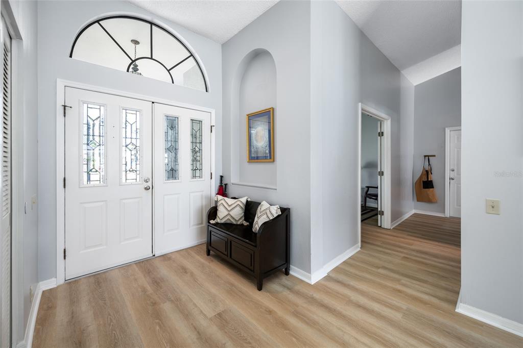An entryway features light wood-look flooring, a white double door, and a built-in wall niche — 3225 HEARTHSTONE COURT, HOLIDAY, FL