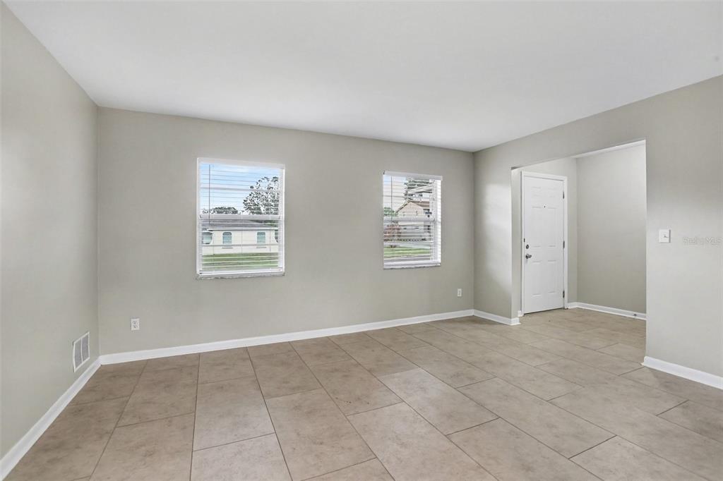An empty room with light gray walls, tile flooring, two windows, and an entryway door — 1909 SHANNONWOOD COURT, BRANDON, FL