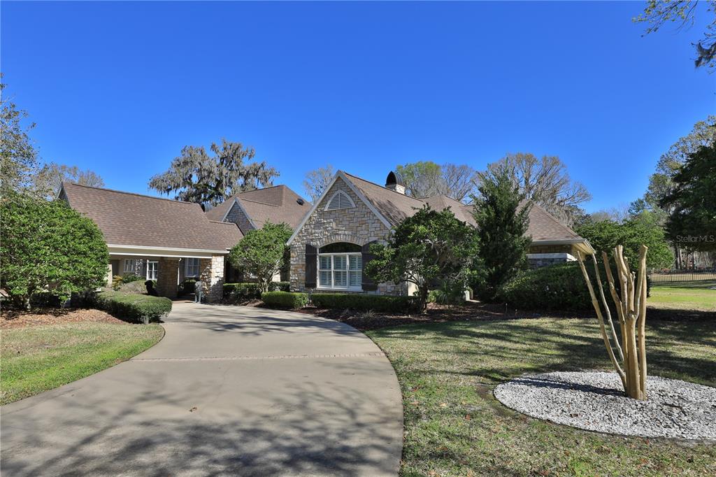 A stone-faced house with a brown shingled roof and a curved concrete driveway — 7963 SE 12TH CIRCLE, OCALA, FL