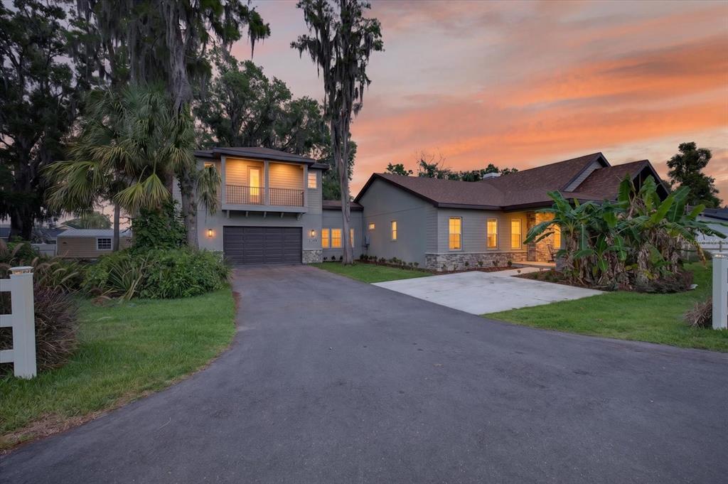 A two-story house with a garage, stone accents, and a driveway at sunset — 1208 SUNSET LANE, LUTZ, FL