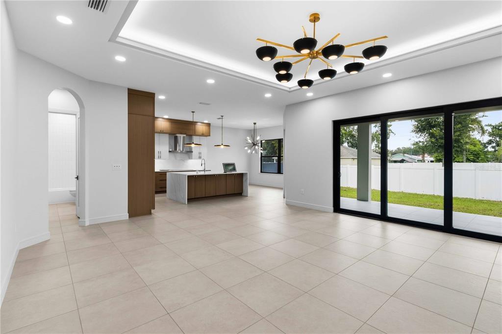 An open-concept living area with tile floors, a modern kitchen, and large sliding glass doors — 104 S MAKI ROAD, PLANT CITY, FL