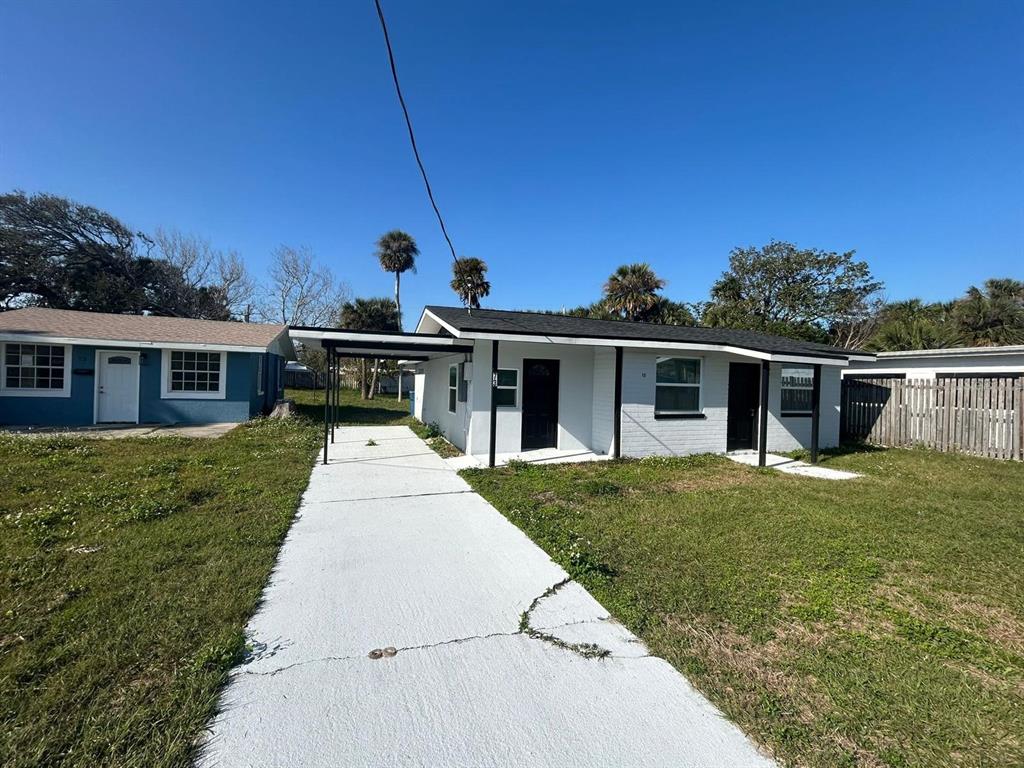 A white, single-story house with a carport and a concrete driveway under a clear sky — 73 BROOKS DRIVE, ORMOND BEACH, FL