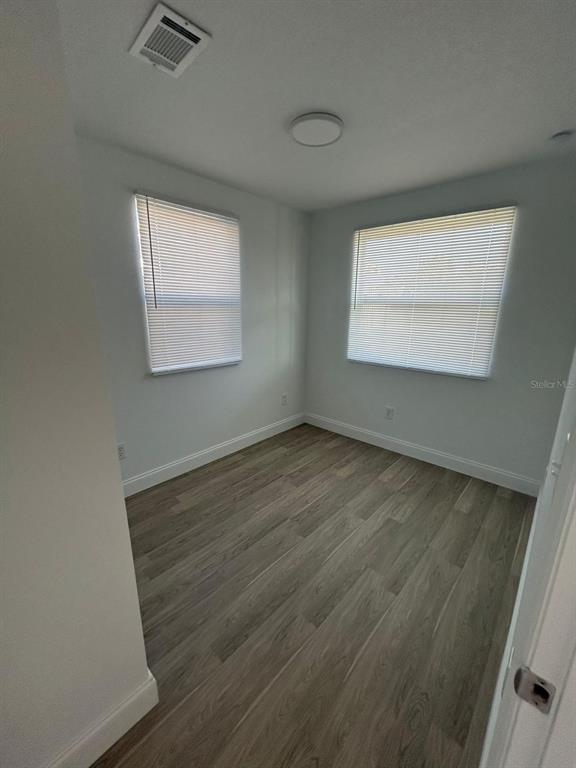 An empty room with light gray walls, wood-look flooring, and two windows with white blinds — 73 BROOKS DRIVE, ORMOND BEACH, FL