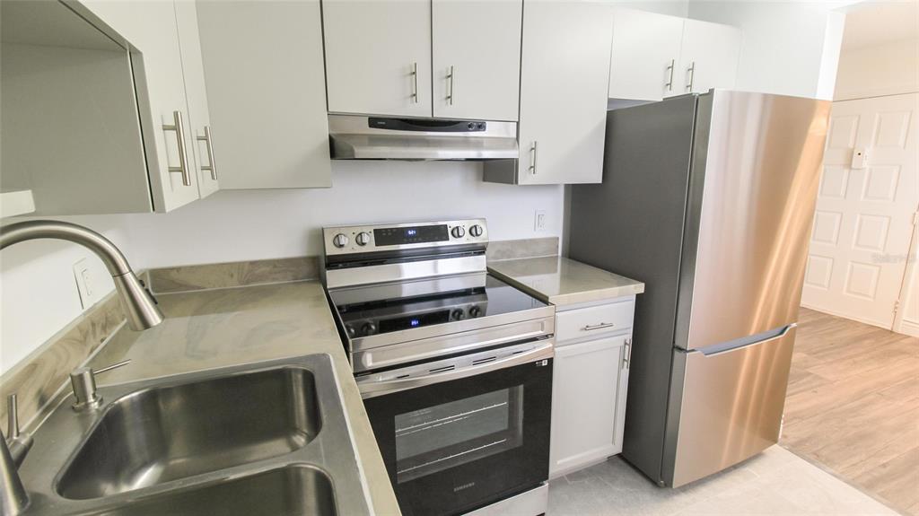 A kitchen features light gray cabinets, stainless steel appliances, and a double-basin sink — 2509 OAK PARK WAY UNIT 115, ORLANDO, FL
