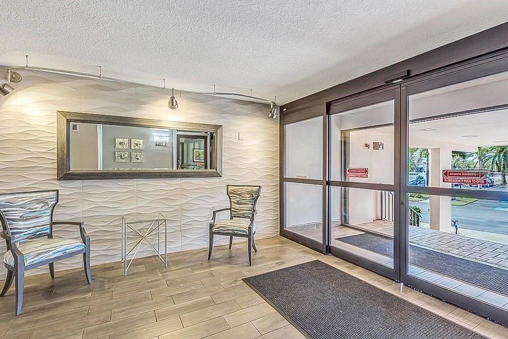 A hallway features two elevators, a wall of mailboxes, and a glass door to outside — 51 ISLAND WAY UNIT 108, CLEARWATER BEACH, FL
