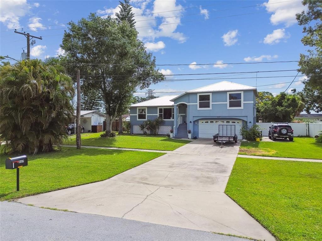 A light blue two-story house with a white roof and a concrete driveway — 317 SHORE DRIVE E, OLDSMAR, FL