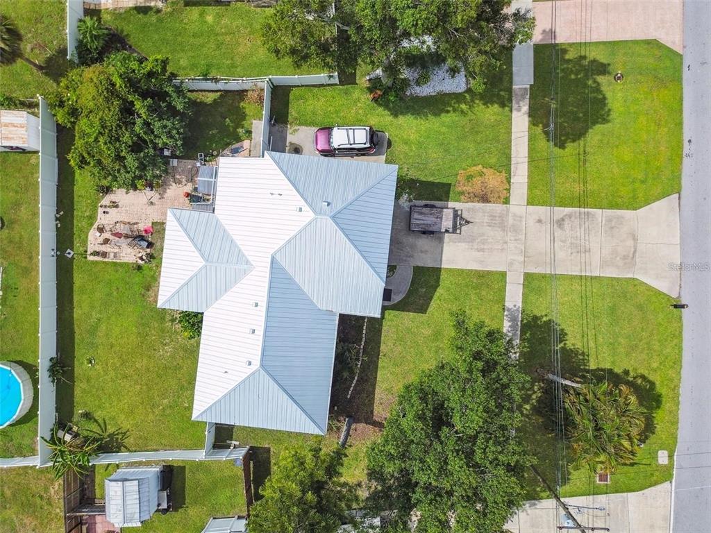 An aerial view shows a house with a metal roof, driveway, and fenced backyard — 317 SHORE DRIVE E, OLDSMAR, FL