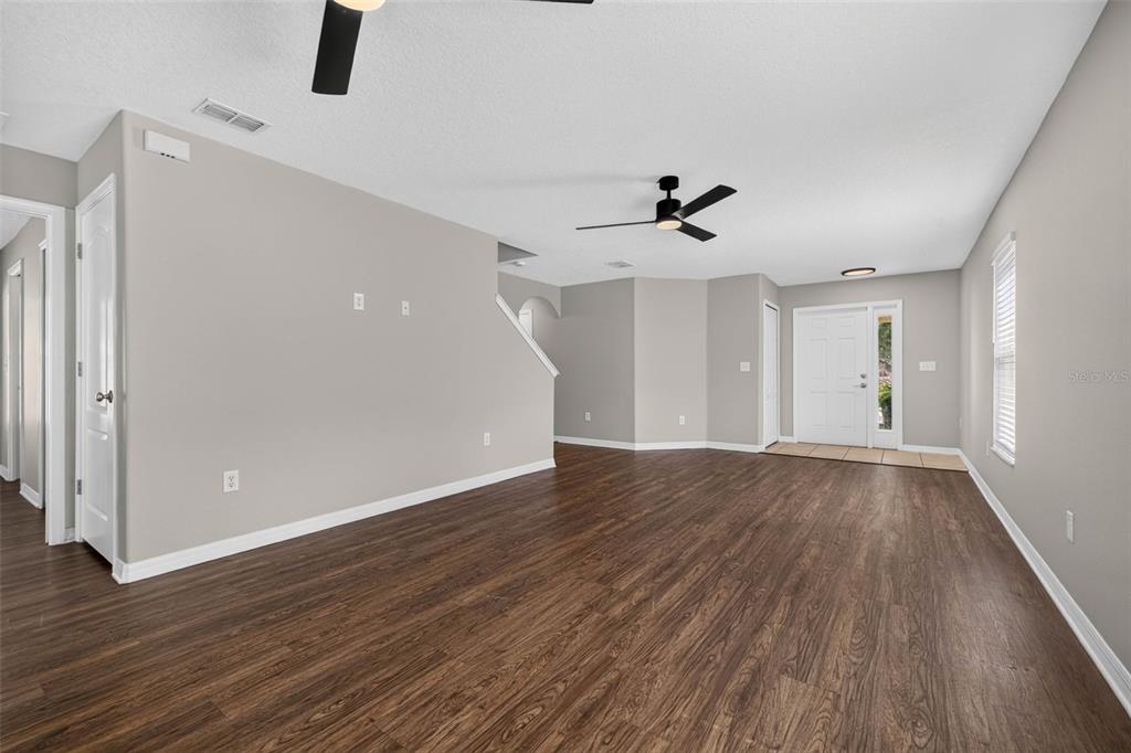 An empty living room features wood-look flooring, light gray walls, and a ceiling fan — 10717 SHADY PRESERVE DRIVE, RIVERVIEW, FL