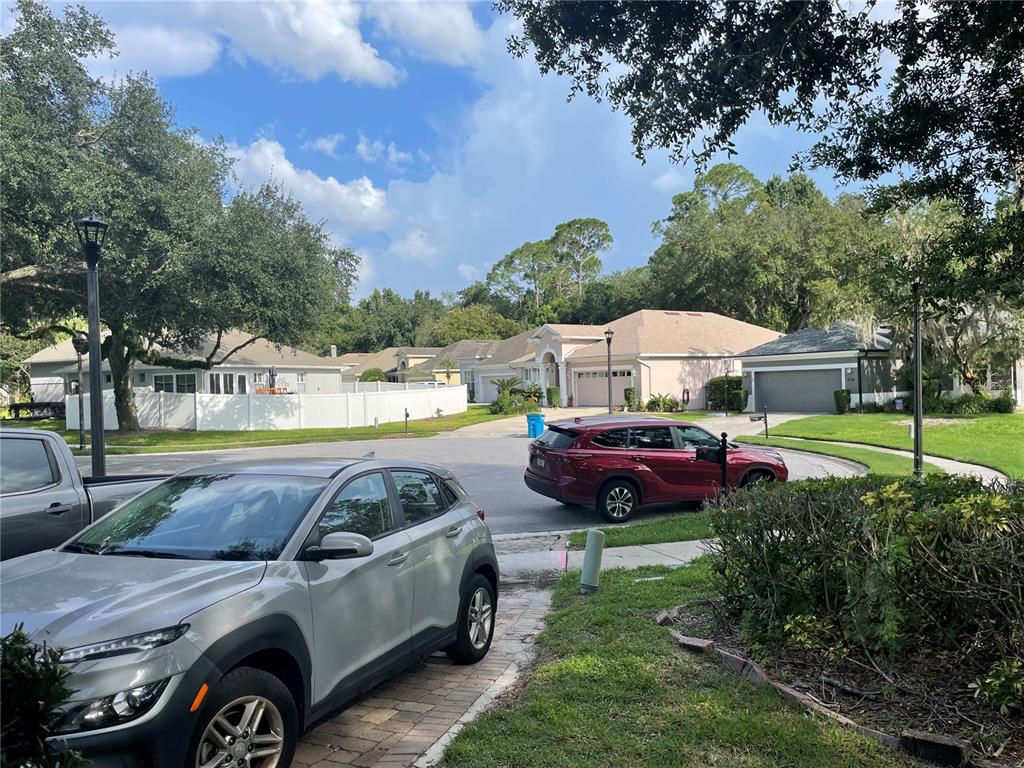 A garage with a gray car, a green trash bin, and storage items on shelves — 133 REDTAIL PLACE, WINTER SPRINGS, FL